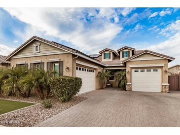 Charming single-Gathering home featuring a three-car garage, brick driveway, and desert landscaping at 20552 E Reins Rd, Queen Creek, AZ 85142