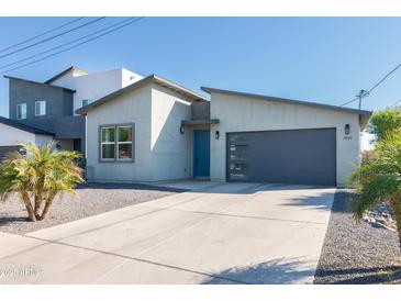 Modern home exterior with a gray garage door, blue front door, and desert landscaping at 2819 N 28Th Pl, Phoenix, AZ 85008
