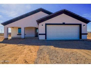 New construction home showcasing a simple landscape and a bright white facade with black trim at 37567 W Roosevelt St, Tonopah, AZ 85354