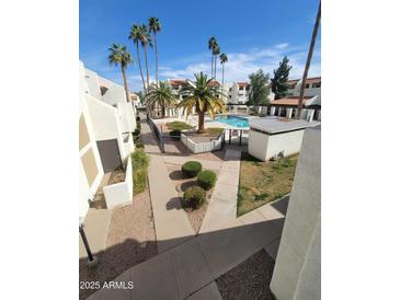 View of a well maintained community pool area with palm trees and multiple buildings, with a walkway at 4730 W Northern Ave # 2109, Glendale, AZ 85301