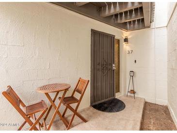 Inviting front entrance with textured walls, brown security door, table and two wood folding chairs at 6240 N 16Th St # 37, Phoenix, AZ 85016