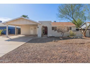 Single-story home featuring desert landscaping, carport and arched entryway with security gate at 8749 W Clarendon Ave, Phoenix, AZ 85037