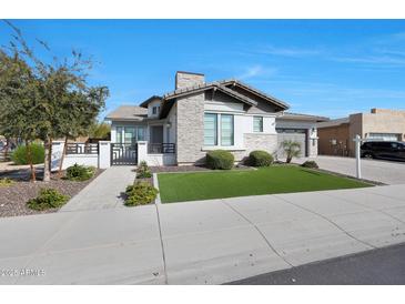 Charming home showcasing a stone facade, three-car garage, lush turf, and inviting curb appeal at 24437 N 94Th Ave, Peoria, AZ 85383