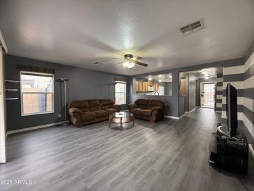 Open-concept living room featuring a ceiling fan, gray walls, and two brown sofas at 1298 S 222Nd Ln, Buckeye, AZ 85326