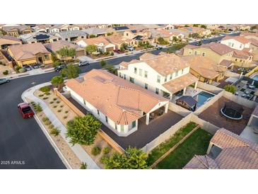 An aerial view of a well-maintained home featuring a sparkling pool and lush green landscaping in a residential neighborhood at 19057 W Yucatan Dr, Surprise, AZ 85388