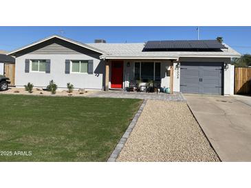 Charming home with a well-manicured front yard, solar panels, a vibrant red door, and stylish gray garage at 2008 E Mitchell Dr, Phoenix, AZ 85016