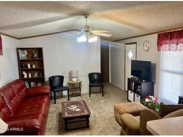 Cozy living room features a plush red sofa, a ceiling fan, and comfortable seating arrangement at 2121 N Center St # 138, Mesa, AZ 85201