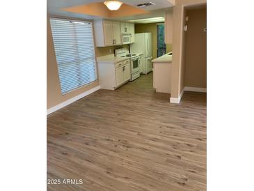 Bright kitchen featuring white cabinets, modern appliances, and wood-look vinyl plank flooring at 3131 W Cochise Dr # 218, Phoenix, AZ 85051