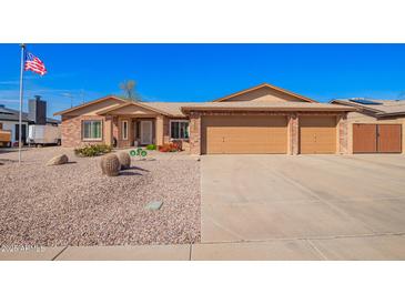 Charming brick home featuring a three-car garage, low maintenance front yard and an American flag in the front at 3408 W Taro Ln, Phoenix, AZ 85027