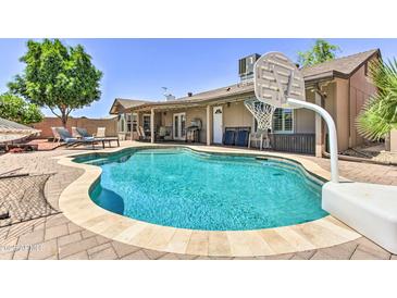 A private backyard oasis features a sparkling pool, lounge chairs, and a basketball hoop for outdoor fun at 8037 W Sweetwater Ave, Peoria, AZ 85381