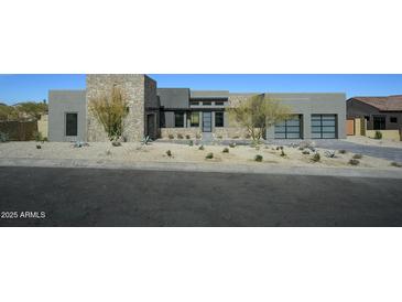 Contemporary home's exterior shows natural stone accents, desert landscaping, and a modern design at 12856 E Rosewood Dr, Scottsdale, AZ 85255
