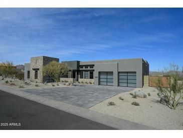 Modern exterior showcasing a contemporary home with a paver driveway and desert landscaping under a blue sky at 12856 E Rosewood Dr, Scottsdale, AZ 85255