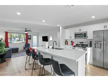 Bright kitchen features stainless steel appliances, white cabinetry, a large island with counter seating at 7407 E Polk St, Scottsdale, AZ 85257