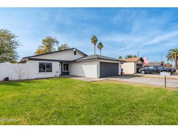 Charming single-story home with a well-maintained lawn and a two-car garage on a sunny day at 8920 N 56Th Ave, Glendale, AZ 85302