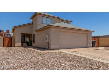 Beige two-story home with a two car garage, desert landscaping, and a well-maintained facade at 11101 N 82Nd Dr, Peoria, AZ 85345