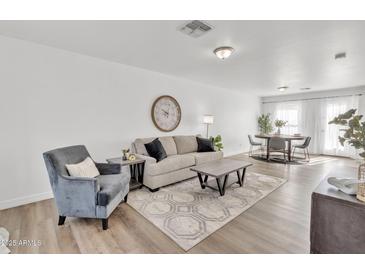 Bright living room with a large rug, stylish furniture, and hardwood floors, creating a welcoming space at 197 E Douglas Ave, Coolidge, AZ 85128