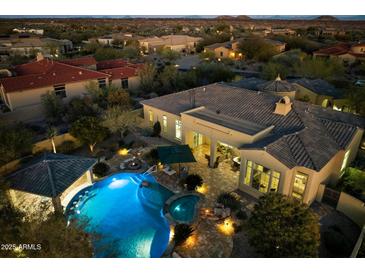 Aerial view of a private pool and spa with a covered bar area and fire pit at dusk at 37080 N 109Th Way, Scottsdale, AZ 85262