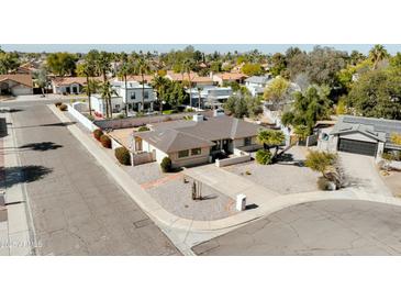 A sunny aerial view of a charming single-story home with a well-kept gravel yard, and palm trees at 4702 E Monte Cristo Ave, Phoenix, AZ 85032