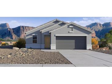 Charming single-story home with a gray exterior, a two-car garage, and a low-maintenance desert landscape in front at 5573 E Rock Bush Ln, San Tan Valley, AZ 85140