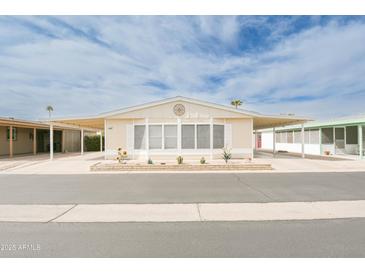 Charming manufactured home with a covered carport and desert landscaping under a bright blue sky at 5735 E Mcdowell Rd # 447, Mesa, AZ 85215