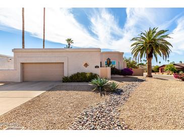 Single-story home with a desert-style rock garden and palm tree in a sunny suburban neighborhood at 6707 E Aire Libre Ln, Scottsdale, AZ 85254