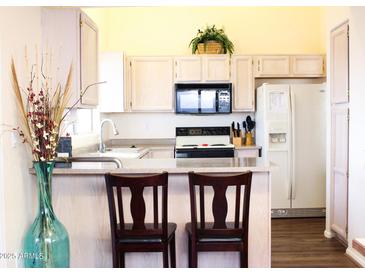 Bright kitchen features light-colored cabinets, breakfast bar with seating, and modern appliances at 14465 W Winding Trl, Surprise, AZ 85374