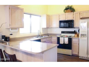 Bright kitchen featuring ample counter space, light-colored cabinets and modern appliances at 14465 W Winding Trl, Surprise, AZ 85374