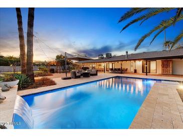 Inviting backyard pool with waterfall feature, covered patio, and outdoor seating, ideal for relaxing evenings at 6323 E Gold Dust Ave, Paradise Valley, AZ 85253