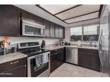 Modern kitchen featuring dark cabinets, stainless steel appliances, and granite countertops at 6405 W Saguaro Dr, Glendale, AZ 85304