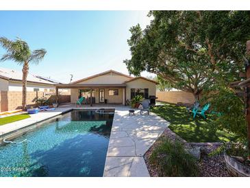 Inviting backyard features a refreshing pool, covered patio, lush greenery, and mature trees, perfect for outdoor enjoyment at 6640 W Honeysuckle Dr, Phoenix, AZ 85083