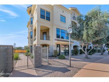 Inviting stucco building featuring a gated entryway, manicured landscaping, and a tile roof at 7295 N Scottsdale Rd # 1004, Paradise Valley, AZ 85253