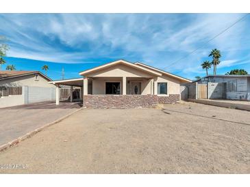 Charming single-story home with a desert landscape, covered porch and carport at 744 E Meadow Ln, Phoenix, AZ 85022