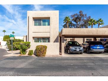 Beige two story condo with a two car covered parking and landscaped yard under a sunny blue sky at 7830 E Park View Dr, Mesa, AZ 85208