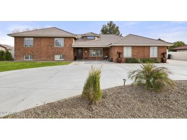 A brick two-story home with large front yard, desert landscaping, and a circular driveway at 9505 S Kenneth Pl, Tempe, AZ 85284