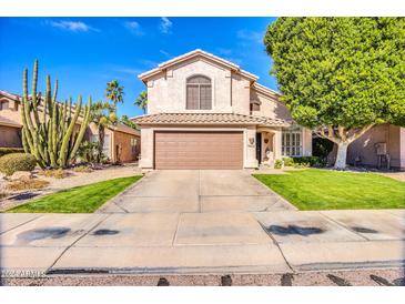 Charming two-story home featuring a well-manicured lawn, mature trees, and desert landscaping at 9652 E Ludlow Dr, Scottsdale, AZ 85260