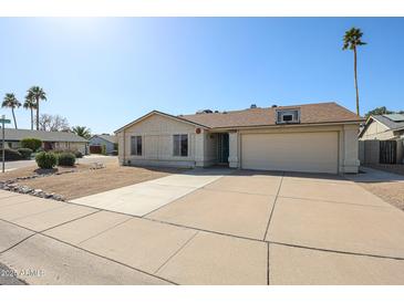 Tan single-story home featuring a two-car garage, low-maintenance desert landscaping, and a basketball hoop above the garage at 10720 E Sahuaro Dr, Scottsdale, AZ 85259