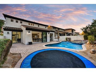 Beautiful backyard with a pool, spa, and trampoline at dusk at 22317 N 39Th Run, Phoenix, AZ 85050