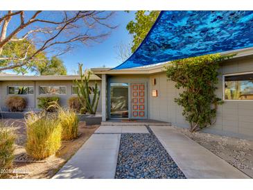 Inviting mid-century home with an elegant walkway, cacti, mature plants, and unique red accents on the front door at 3237 E Meadowbrook Ave, Phoenix, AZ 85018