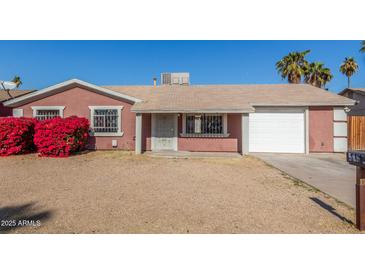 Charming single-story home with desert landscaping, a garage, and vibrant red bougainvillea bushes at 5952 W Coronado Rd, Phoenix, AZ 85035