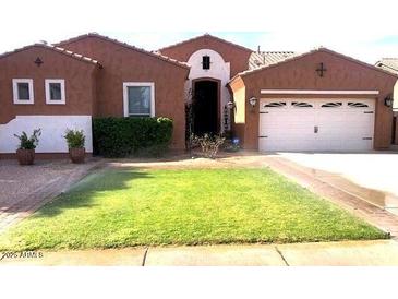 Charming single-story home with a lush green lawn, desert landscaping, and a two-car garage at , Gilbert, AZ 85234