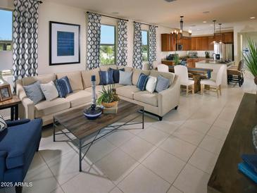 Bright living room featuring an L-shaped couch, tile floors, and an open floor plan to the kitchen and dining area at 20670 N Confetti Ct, Maricopa, AZ 85138