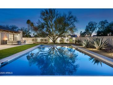 Stunning pool with a large tree in the background reflecting on the water at twilight at 22619 N La Senda Dr, Scottsdale, AZ 85255