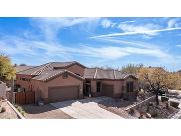 Stunning home featuring a three car garage, desert landscaping, and a tile roof set against a beautiful blue sky at 4109 N Twilight Cir, Mesa, AZ 85207