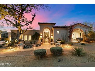 Stunning home featuring charming landscaping and a picturesque wrought iron gate entrance at sunset at 9290 E Thompson Peak Pkwy # 142, Scottsdale, AZ 85255