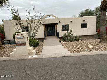 Charming single-story home with a light-colored exterior, desert landscaping, and a welcoming entrance at 11407 N Pinto Dr, Fountain Hills, AZ 85268