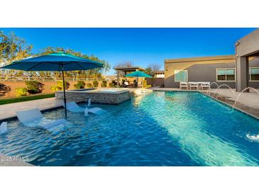 Resort style pool with in-pool loungers, hot tub, and a lush backyard at 19912 E Natalie Way, Queen Creek, AZ 85142