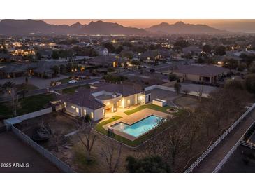 Stunning aerial view of property featuring a pool, backyard fire pit, lush landscaping and a mountain backdrop at 21442 E Excelsior Ave, Queen Creek, AZ 85142