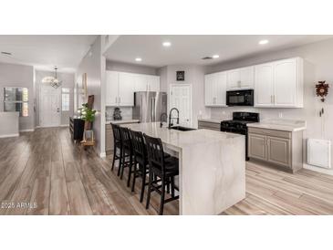Modern kitchen with a large waterfall island, stainless steel appliances, white cabinets, and wood-look tile flooring at 3765 E Del Rio St, Gilbert, AZ 85295