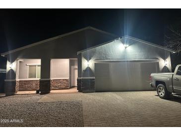 Night view of the home's exterior featuring stone accents and a two-car garage with a truck parked in front at 4835 S 35Th Dr, Phoenix, AZ 85041