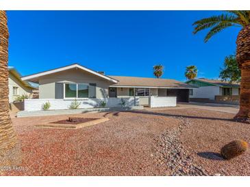 Charming single-story home features a low white brick wall, desert landscaping and mature palm trees at 1206 E Loyola Dr, Tempe, AZ 85282